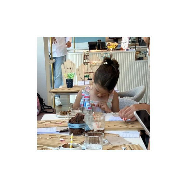girl making their own Murmures Precieux® dash and dot jewellery DIY bracelet and necklace-making workshop
